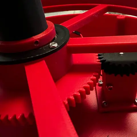 Black motor pinion meshing with the red rotor gear beside the central lamp mast.